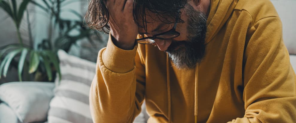Hombre sosteniendo su cabeza con aspecto de preocupación | Esvidas Hombre sosteniendo su cabeza con aspecto de preocupación