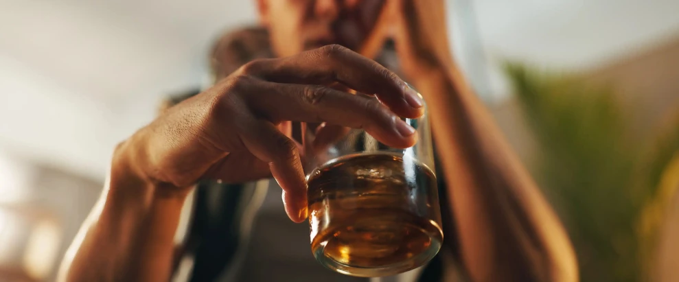 Hombre con un vaso de alcohol en la mano pensando en cómo dejar de beber